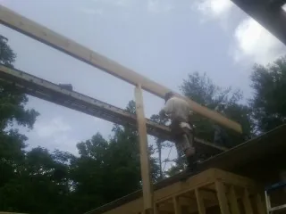 Carpenter setting a ridge beam over a new addition frame — Ice Dam Removal by Roofing Brothers in Placentia