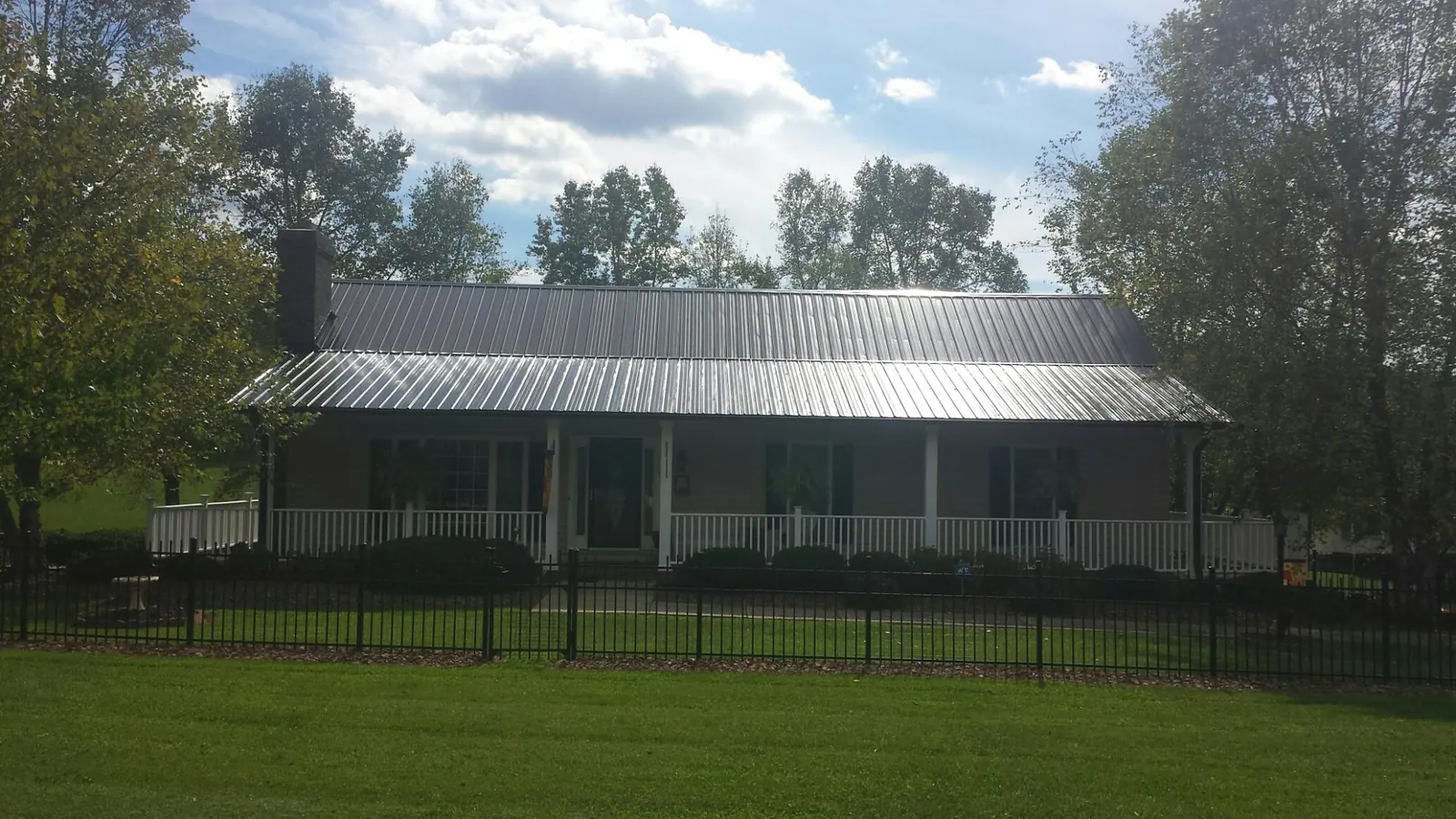 Gray metal roof on a brick ranch with a full width front porch — Gutter Guard Installation work by our crew in Placentia