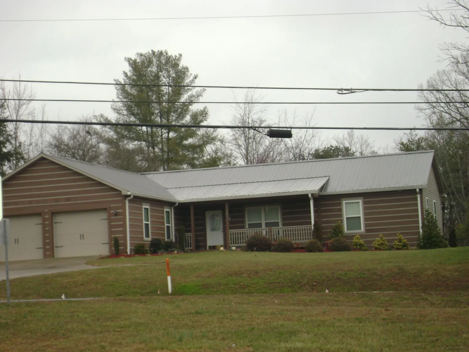 Gray metal roof on a log sided ranch home with a front porch in Placentia