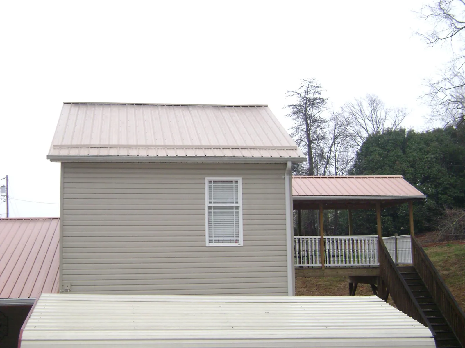 Tan metal roofs on a two story addition and attached porch, from a Roof Replacement job in Placentia