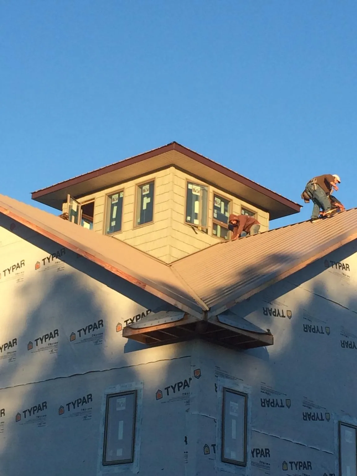 Roofers working around a rooftop cupola on a new metal roof at sunset — Roof Waterproofing in Placentia by Roofing Brothers